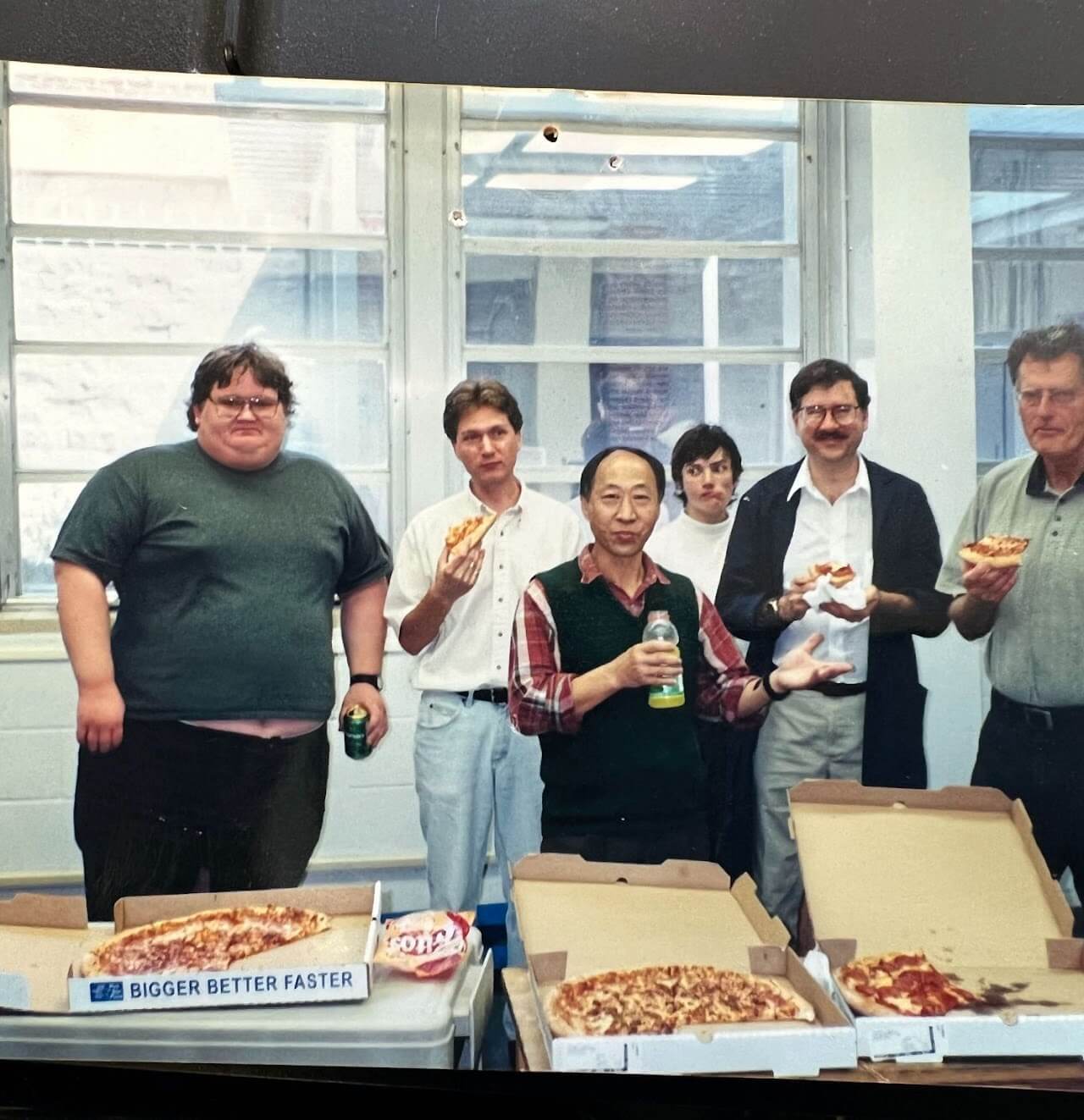 group of people posing next to pizzas indoors